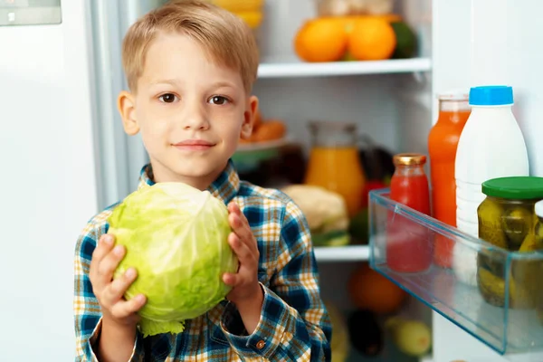 Little boy standing in front of open fridge and choosing food — Stock Photo, Image