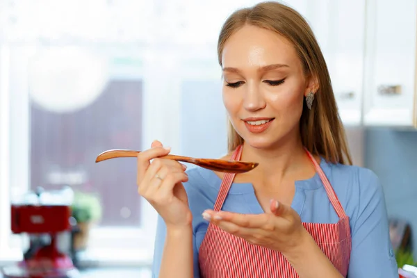 Atractiva joven rubia revisando comida cocinada —  Fotos de Stock