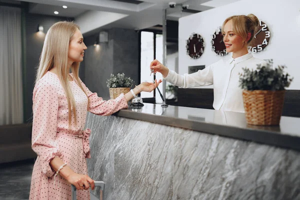 Ung kvinna hotell gäst får nyckelkort från receptionist — Stockfoto