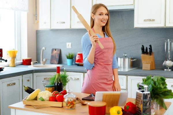 Atractiva joven en delantal rojo de pie en su cocina —  Fotos de Stock
