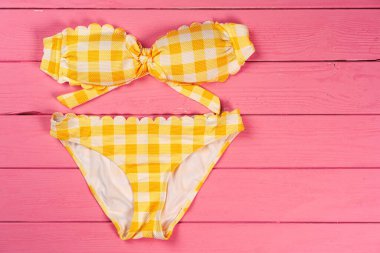 Parlak pembe ahşap arka planda sarı bikini