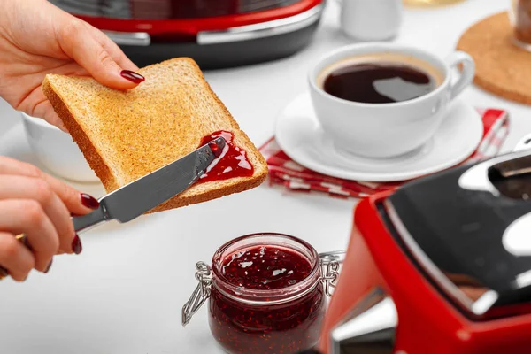 Kvinde hånd spresding jordbær marmelade på bagt toast - Stock-foto