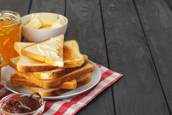 Кусок свежего хлеба с маслом и джемом на столе