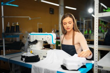 Güzel kadın terzi işyerinde kumaşla çalışıyor.