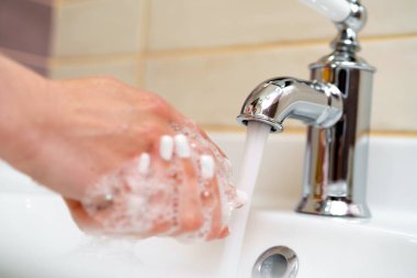 Kadın ellerini sabunla yıkıyor.