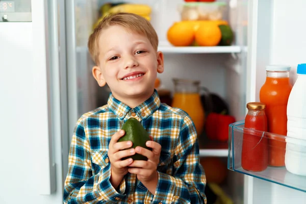 Little boy standing in front of open fridge and choosing food — Stock Photo, Image