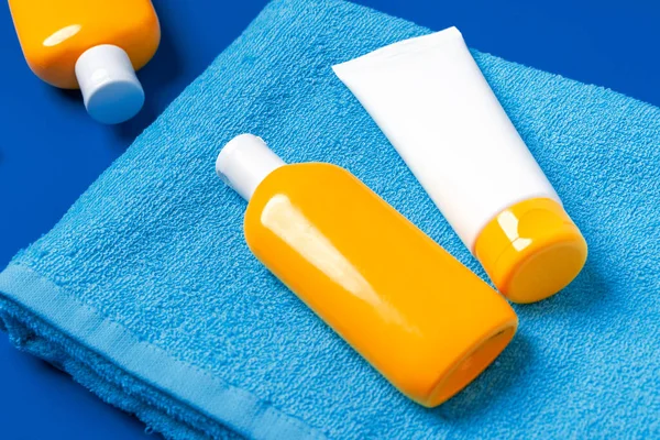 Zonnebrandcrème flessen op blauw strand handdoek close-up — Stockfoto