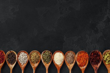 Siyah arka planda çeşitli baharatlı ahşap kaşıklar.