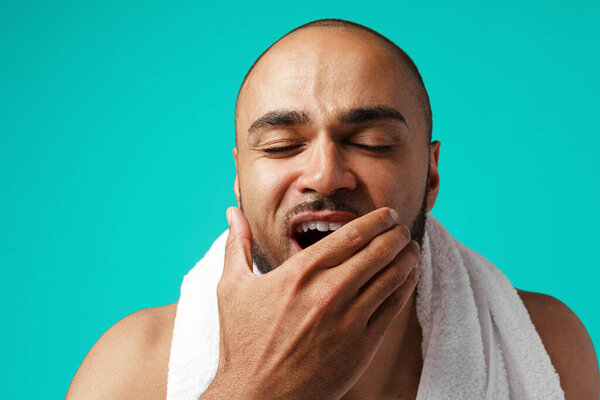Close-up portrait of a sleepy black man with towel in the morning