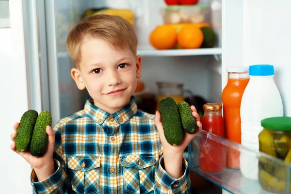 オープン冷蔵庫の前に立って食べ物を選ぶ小さな男の子 — ストック写真