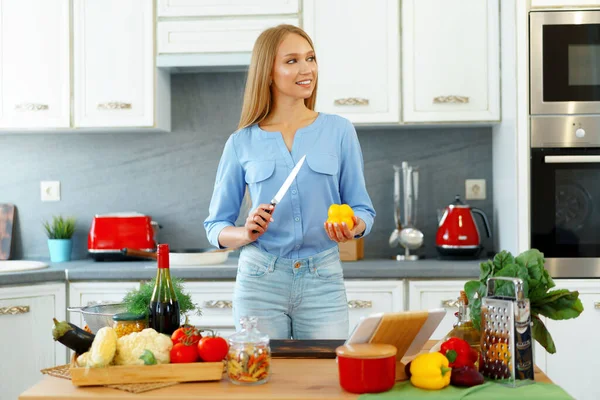 Joven hermosa mujer caucásica cocinar y el uso de su tableta digital en la cocina —  Fotos de Stock