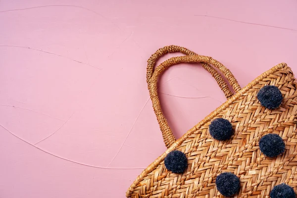 Elegante bolso de paja con bubos azules decorativos sobre fondo rosa — Foto de Stock