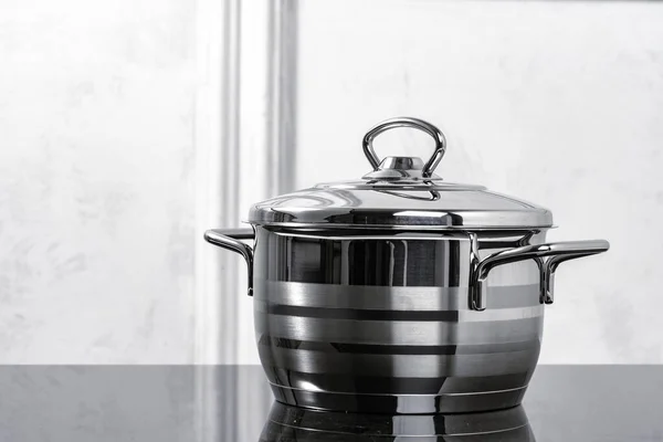 Ustensiles de cuisine en aluminium sur cuisinière à induction noire contre mur gris — Photo