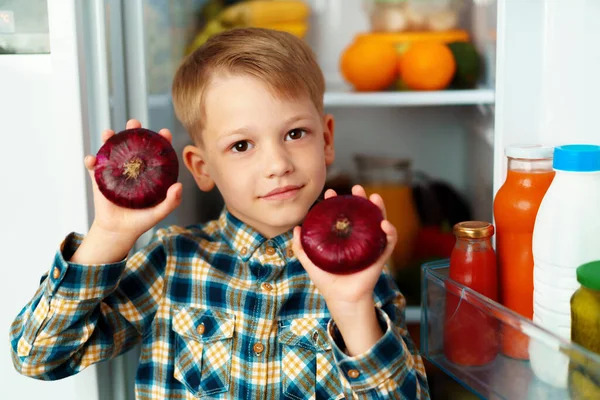 Little boy standing in front of open fridge and choosing food