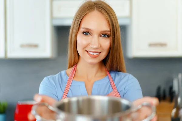 Mulher loira jovem atraente verificando alimentos cozidos — Fotografia de Stock