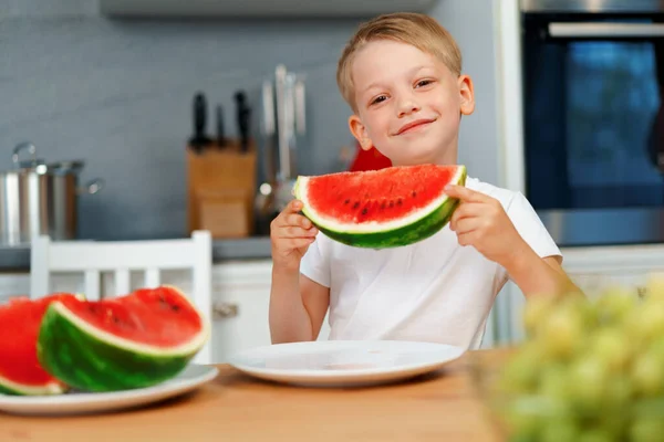 台所でスイカの作品を食べる小さな男の子 — ストック写真