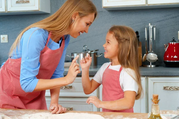 Bela mãe e sua adorável filha se divertindo na cozinha enquanto cozinha comida — Fotografia de Stock
