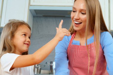 Genç sarışın kadın, anne ve çocukları hamur pişirirken eğleniyorlar.