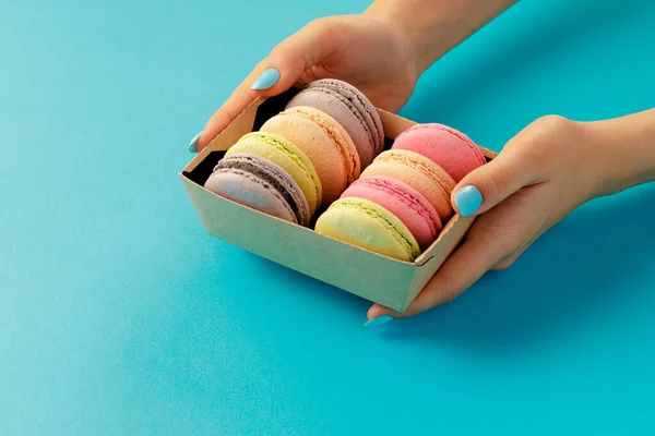 Mãos femininas segurando caixa com cookies macaroon coloridos — Fotografia de Stock