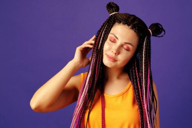 Afrika örgülü genç beyaz kadın kulaklıkla müzik dinliyor.