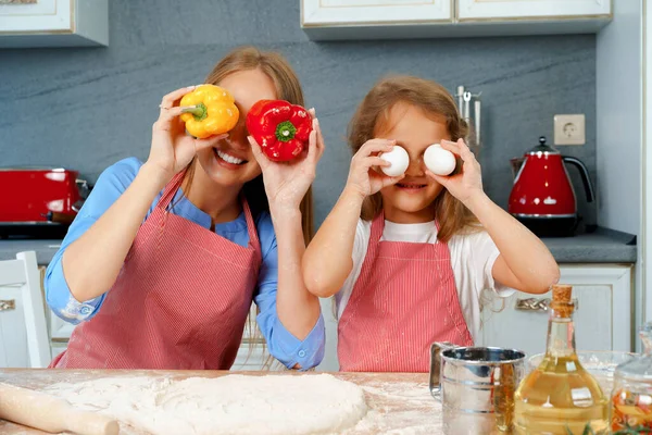 Mooie moeder en haar schattige dochter hebben plezier in de keuken tijdens het koken eten — Stockfoto