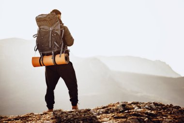 Yürüyüşçü dağın tepesine çıktı ve aşağı vadiye baktı.