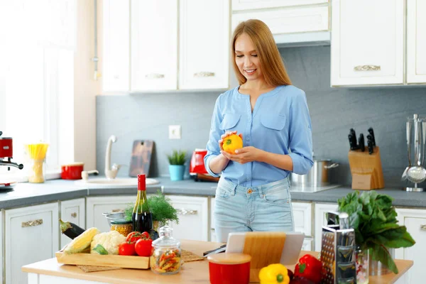 Jovem bela mulher caucasiana cozinhar e usar seu tablet digital na cozinha — Fotografia de Stock