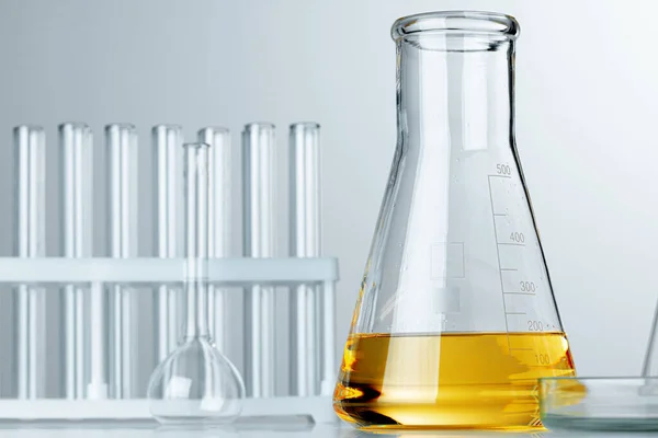 Laboratóriumi üvegáru sárga olajos folyadékkal szürke alapon — Stock Fotó