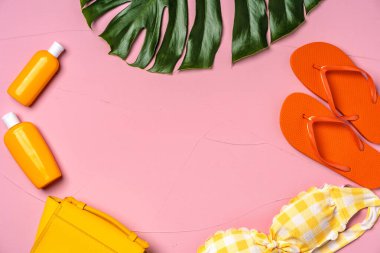 Bikinili tatil konsepti, parmak arası terlikler ve pembe kremli güneş kremleri.