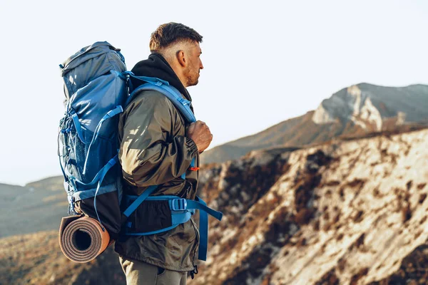 Young caucasian man traveler with big backpack hiking in the mountains — Stock Photo, Image