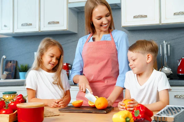 Mother cooking with her children in kitchen — Stock Photo, Image