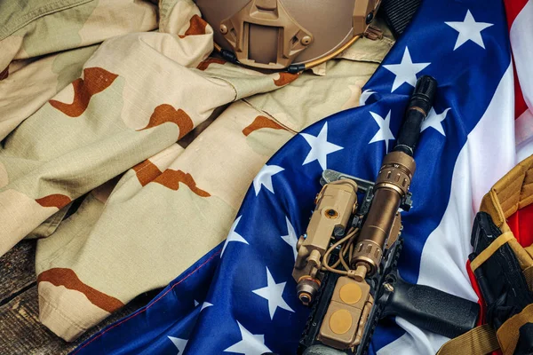Bandera de batalla estadounidense y rifle de asalto en la mesa de madera . — Foto de Stock