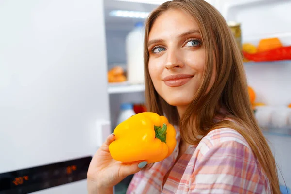 Porträtt av en ung blond kvinna som tar mat från kylskåpet — Stockfoto