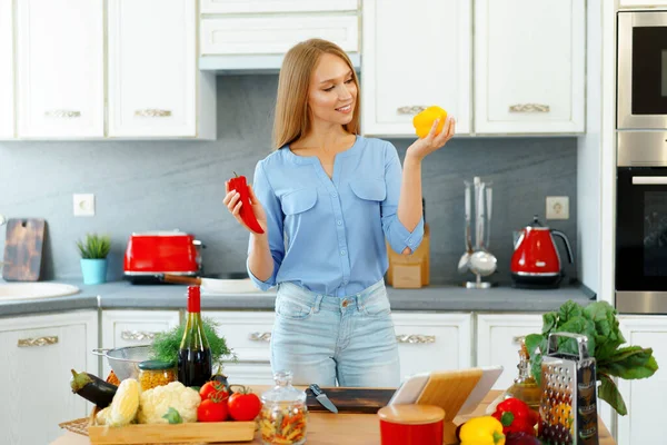 Jovem bela mulher caucasiana cozinhar e usar seu tablet digital na cozinha — Fotografia de Stock