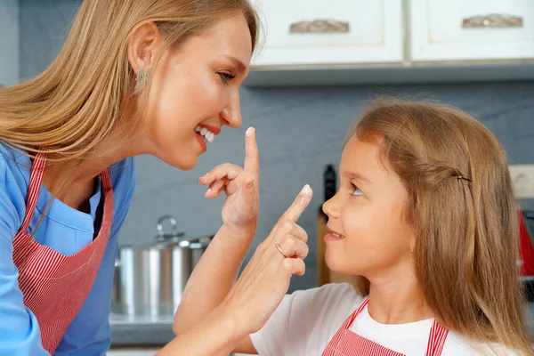 Mooie moeder en haar schattige dochter hebben plezier in de keuken tijdens het koken eten — Stockfoto