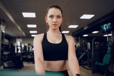 Çekici genç bir kadın kollarının kasları için egzersiz yapıyor ve spor salonuna geri dönüyor.