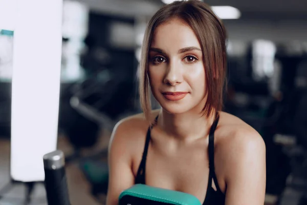 Junge schöne Frau trainiert ihre Arme in einem Fitnessgerät — Stockfoto