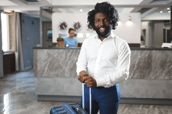 Svart affärsman med packat bagage stående i hotellets lobby — Stockfoto
