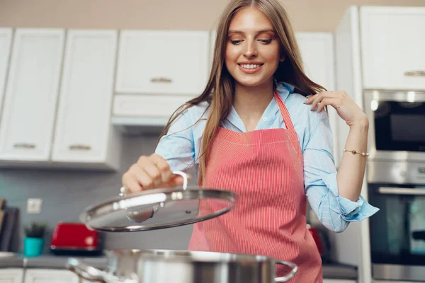 Niza joven cocina algo junto a la estufa en su cocina —  Fotos de Stock