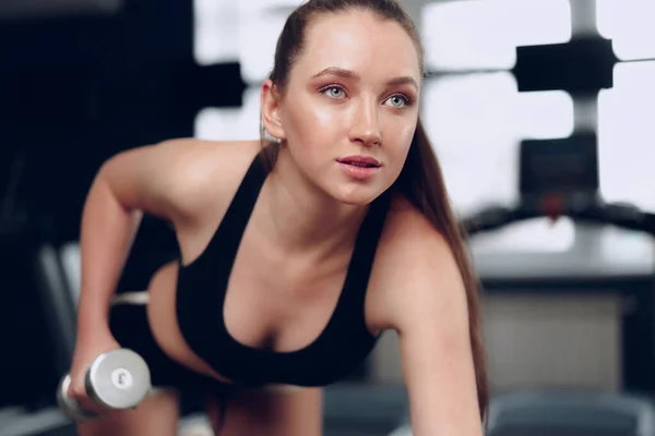 Νεαρή μελαχρινή σπορ γυναίκα άσκηση με αλτήρα σε ένα γυμναστήριο — Φωτογραφία Αρχείου
