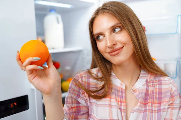 Retrato de una joven rubia tomando comida de su nevera — Foto de Stock