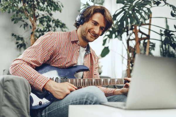 전자 기타를 연주하고 노트북으로 음악을 녹음하는 사람 — 스톡 사진