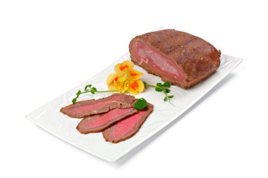 Beyaz tabakta ince dilimlenmiş sosis parçaları.