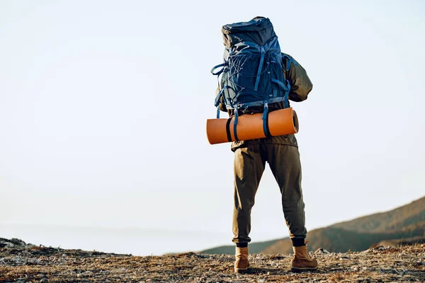 Homem caminhante chegou ao topo da montanha e olha para baixo para o vale — Fotografia de Stock