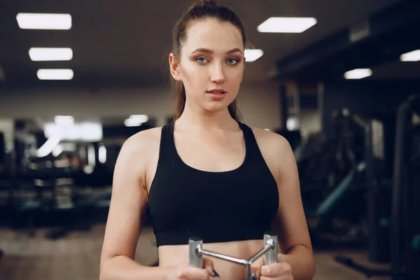 आकर्षक युवा महिला जिम में हाथों की मांसपेशियों के लिए व्यायाम कर रही है और वापस — स्टॉक फ़ोटो, इमेज