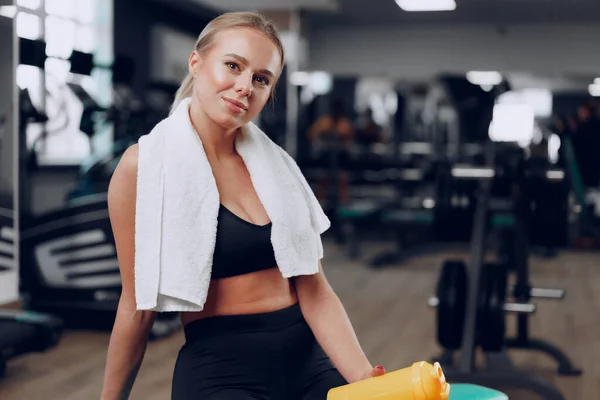 운동하는 젊은 여자가 운동 후 체육관에서 술을 마시고 있다 — 스톡 사진