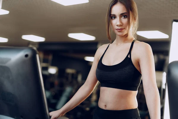 Ziemlich fitte Frau im schwarzen Sportanzug beim Training auf dem Laufband — Stockfoto