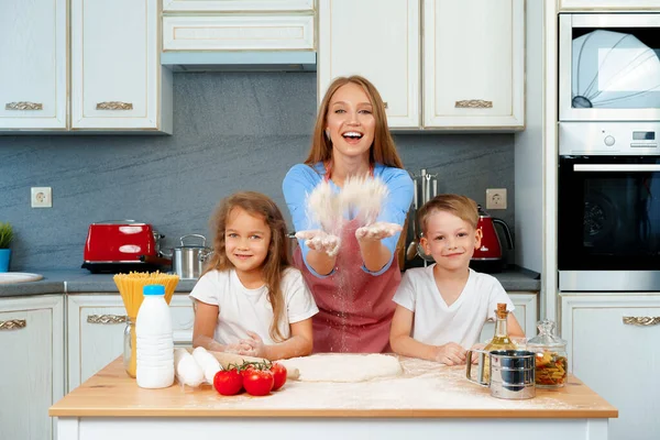 Jovem mulher loira, mãe e seus filhos se divertindo enquanto cozinha massa — Fotografia de Stock