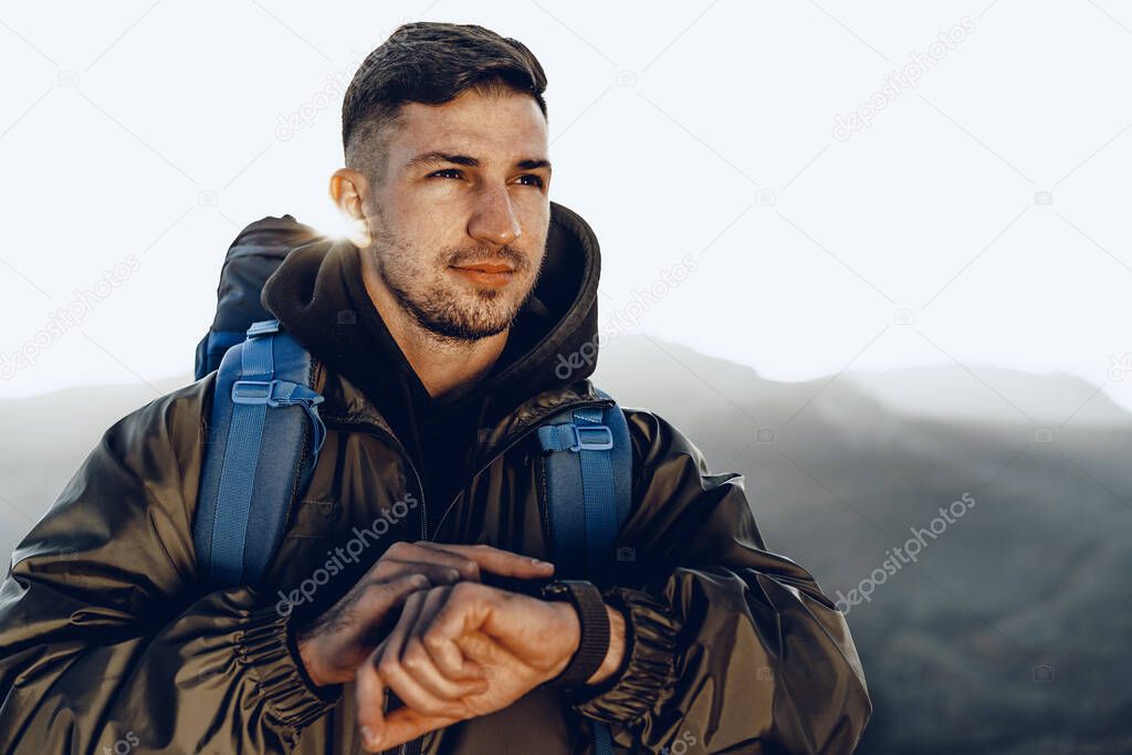 Young male traveler looking at his smart watch