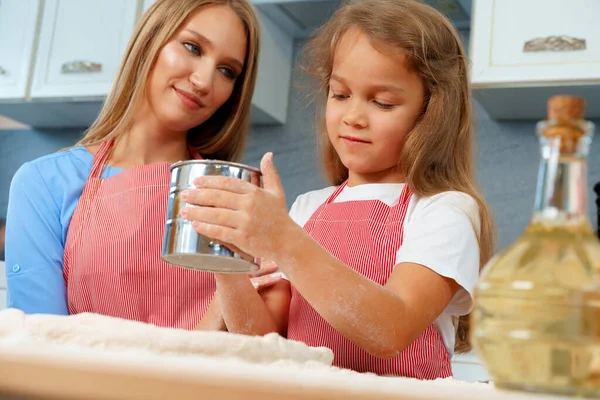 Moeder en haar dochtertje maken deeg klaar in de keuken — Stockfoto